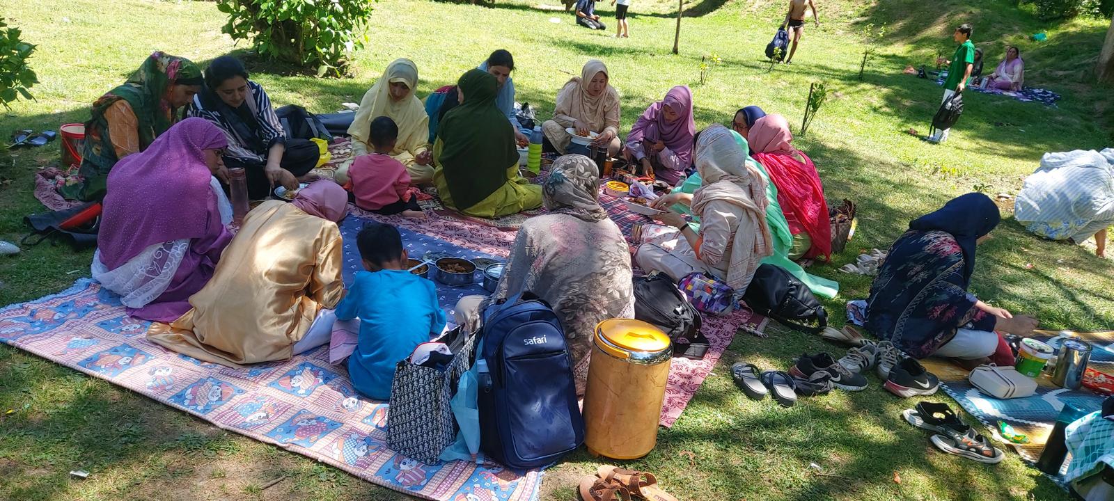 Women and children gathered on blankets for a shared outdoor meal in India